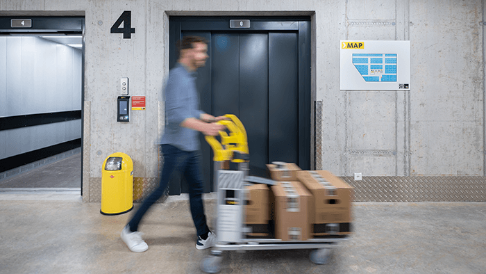 A young man is exiting the lift with a trolley in a Zebrabox location